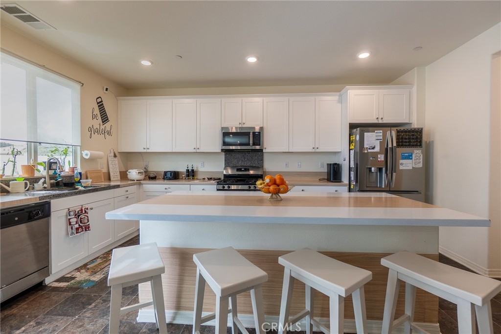 1099 Little Leaf Street Calimesa, CA 92320 - Photo 8 of 32 a kitchen with kitchen island granite countertop white cabinets and refrigerator