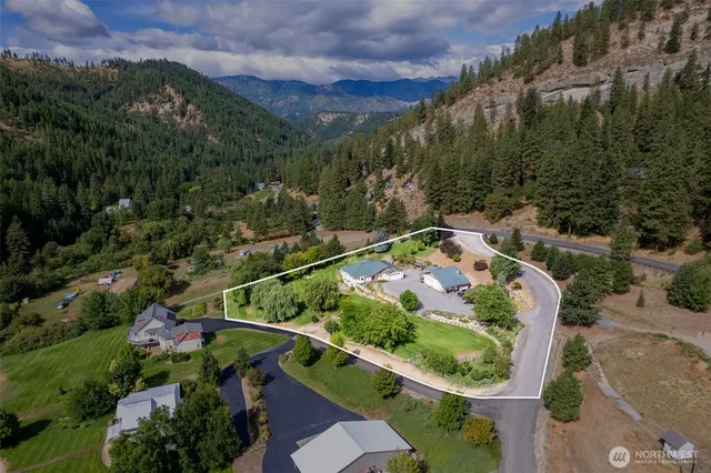 an aerial view of residential house with outdoor space and trees all around