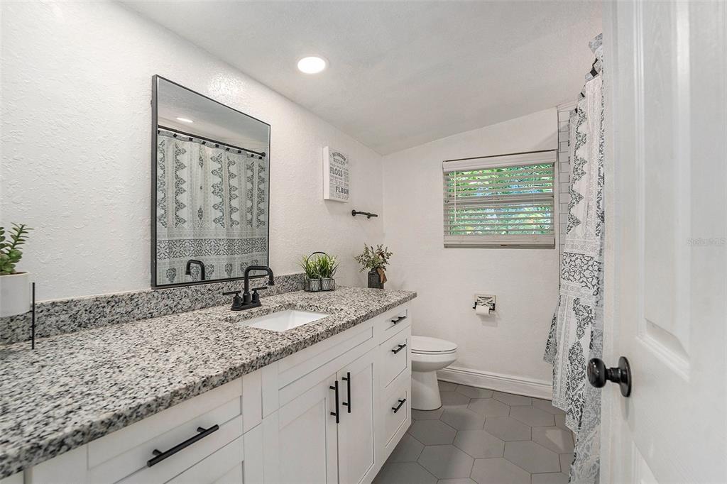 4921 6th Street Zephyrhills, FL 33542 - Photo 11 of 15 a bathroom with a granite countertop sink toilet and mirror
