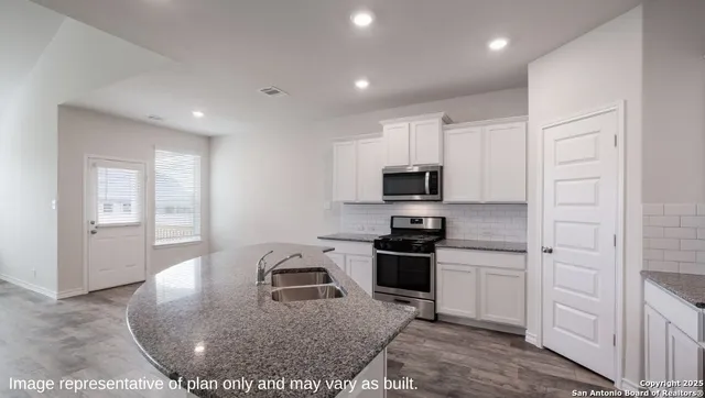 a kitchen with stainless steel appliances granite countertop a stove a sink and a refrigerator