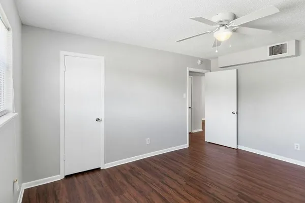 an empty room with wooden floor and ceiling fan