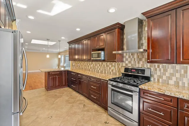 a kitchen with stainless steel appliances granite countertop a stove a sink and a microwave