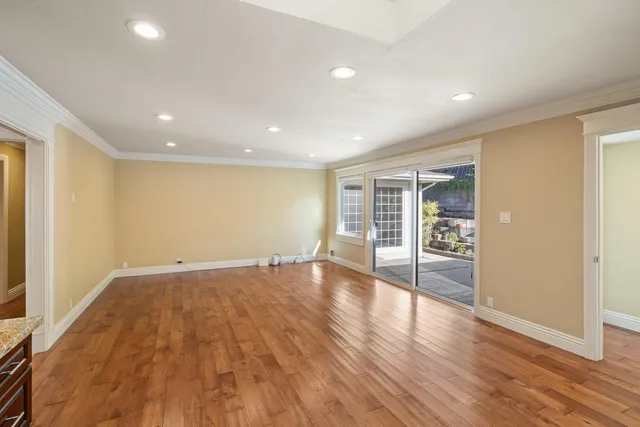 a view of an empty room with wooden floor and a window