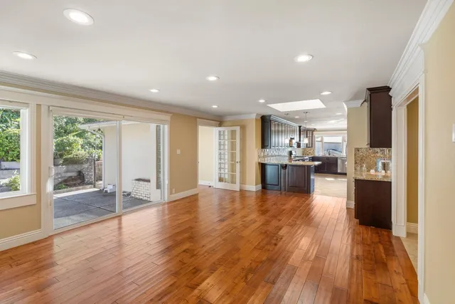 a view of a kitchen with kitchen island wooden floors stainless steel appliances and windows