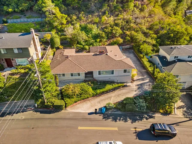 an aerial view of a house with a yard and a large tree