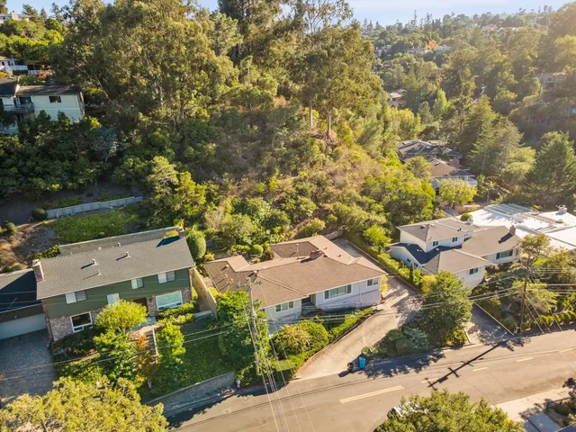 an aerial view of a house with a yard and mountain view in back