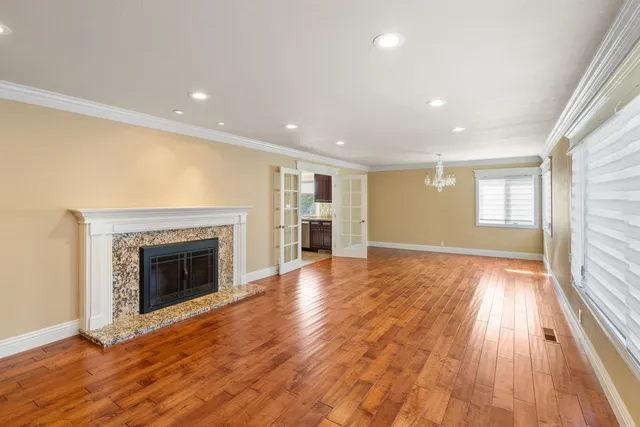 an empty room with wooden floor fireplace and windows