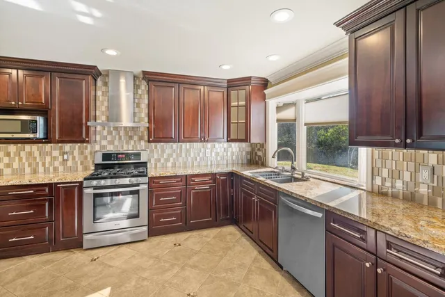 a kitchen with stainless steel appliances granite countertop a sink a stove and a microwave
