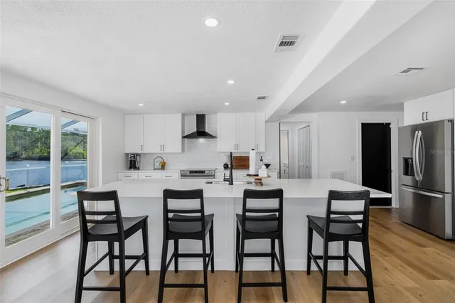 a dining area with stainless steel appliances kitchen island granite countertop a dining table chairs and a refrigerator