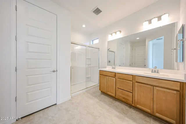 a bathroom with a double vanity sink a mirror and a shower