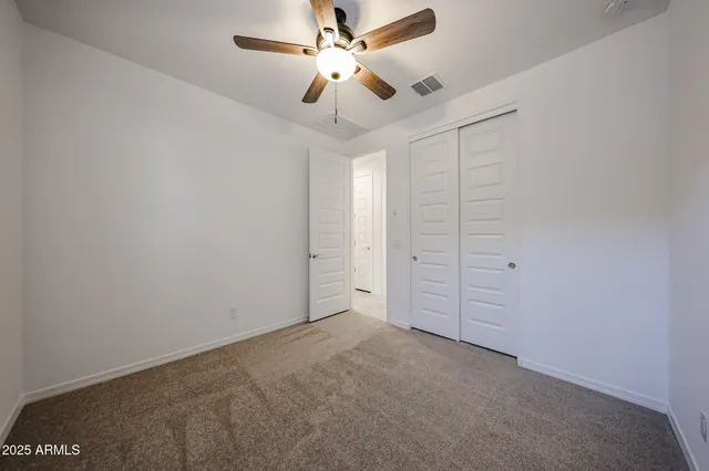 en empty room with closet and ceiling fan