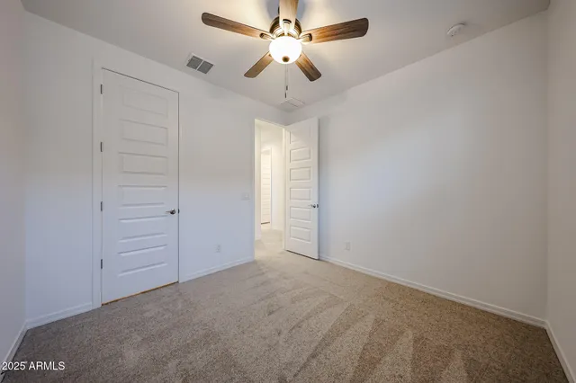 an empty room with closet and a ceiling fan