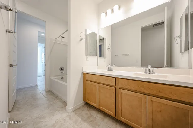 a bathroom with a double vanity sink a mirror and a bathtub
