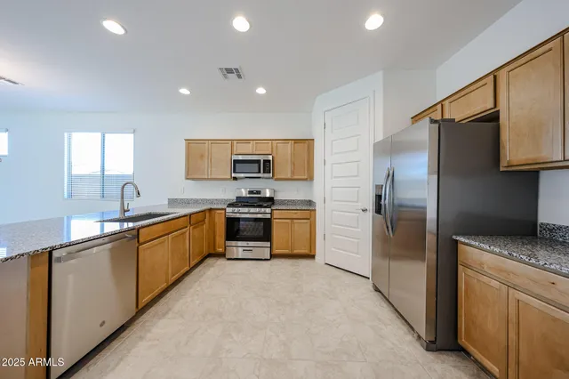 a kitchen with stainless steel appliances granite countertop a refrigerator sink and stove