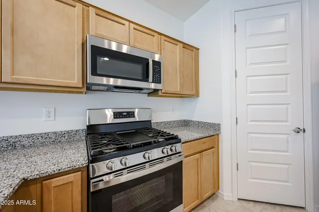 a kitchen with stainless steel appliances granite countertop white cabinets and a stove top oven