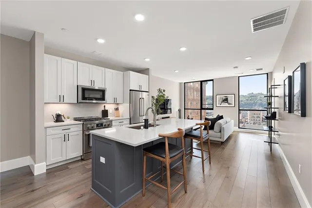 a kitchen with a stove a sink a refrigerator and a view of living room