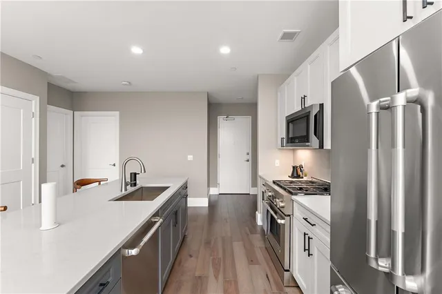 a kitchen with stainless steel appliances granite countertop white cabinets a refrigerator and a stove top oven