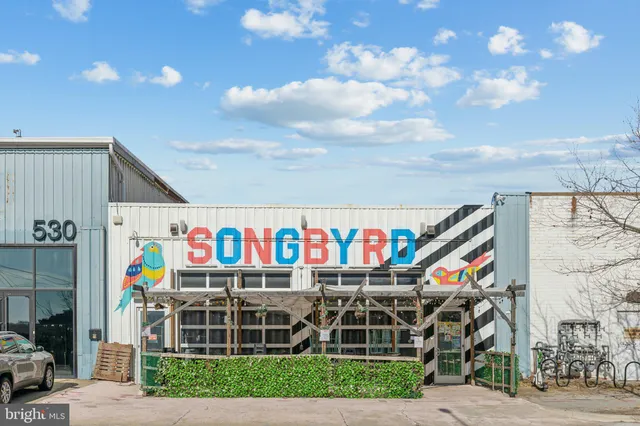 a front view of a building with retail shops and trees