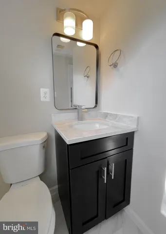 a bathroom with a granite countertop toilet sink and mirror