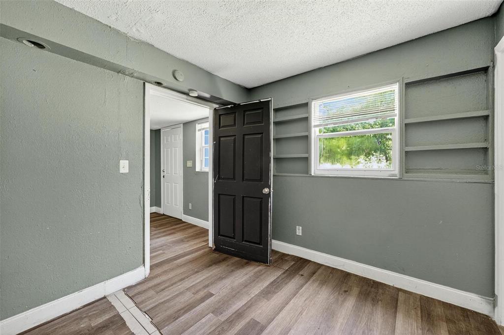 1257 North Pine Hills Road Orlando, FL 32808 - Photo 11 of 35 a view of an empty room with wooden floor and a window