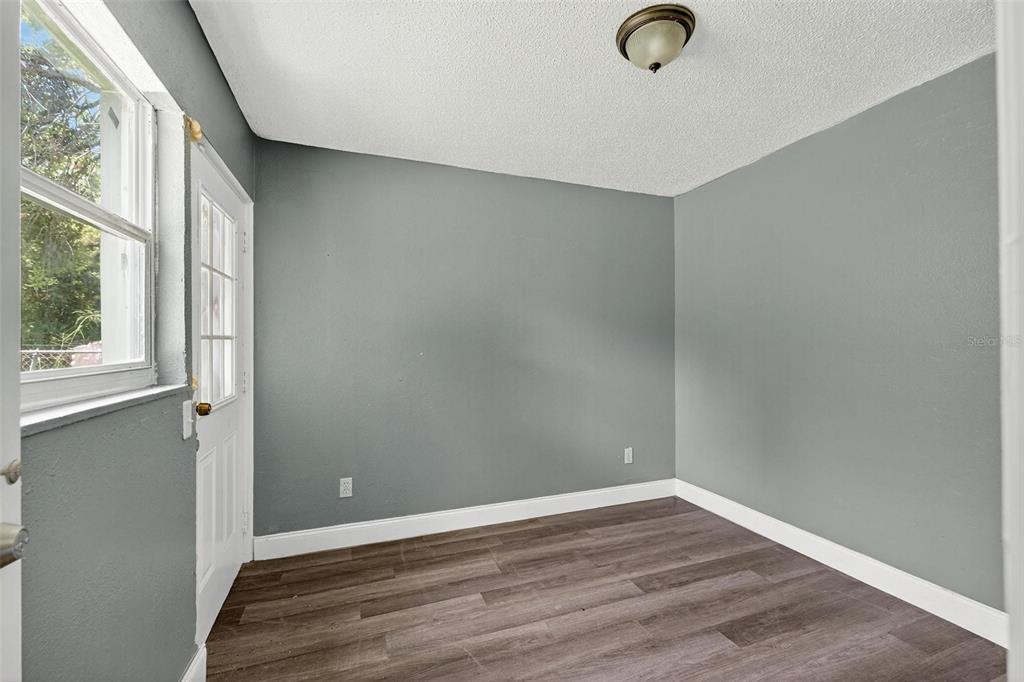 1257 North Pine Hills Road Orlando, FL 32808 - Photo 12 of 35 an empty room with wooden floor and windows