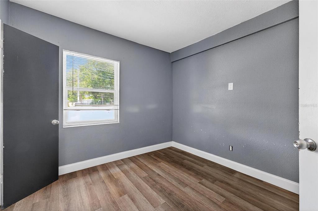 1257 North Pine Hills Road Orlando, FL 32808 - Photo 23 of 35 a view of an empty room with wooden floor and a window
