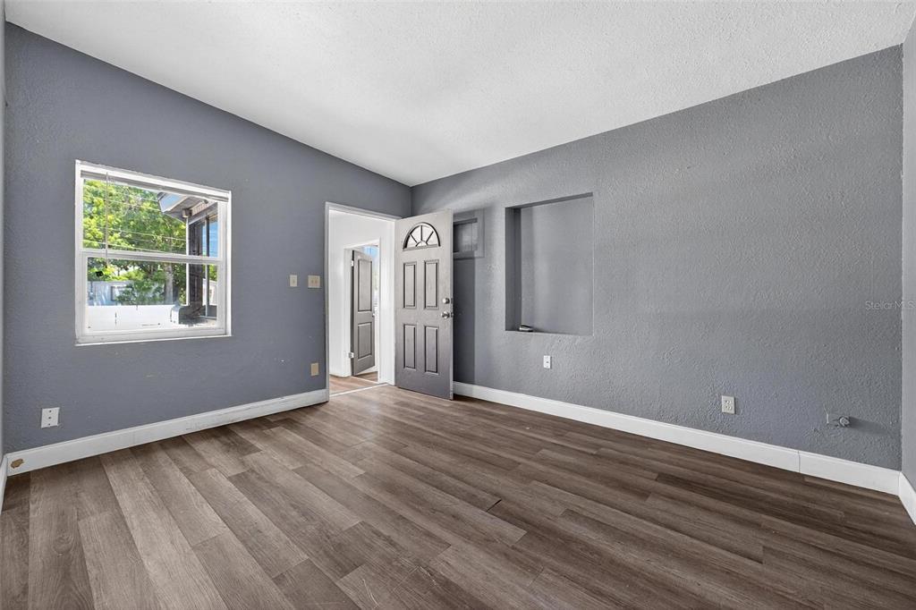 1257 North Pine Hills Road Orlando, FL 32808 - Photo 4 of 35 a view of an empty room with wooden floor and a window