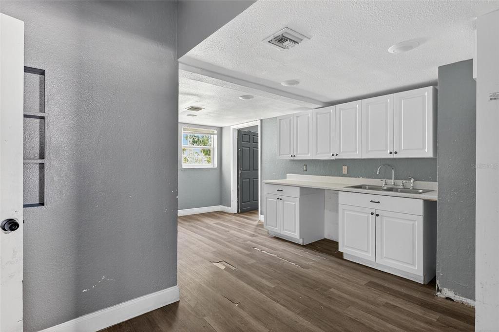 1257 North Pine Hills Road Orlando, FL 32808 - Photo 5 of 35 a view of a kitchen with white cabinets and wooden floor