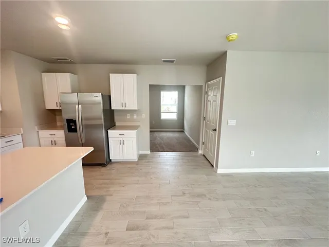 a large kitchen with a refrigerator a stove top oven and white cabinets