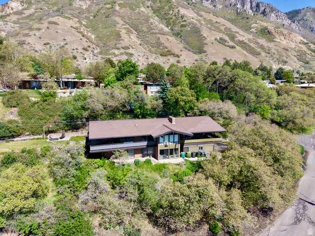 1900 North 100 East Provo, UT 84604 - Photo 2 of 49 nestled into a hillside, featuring a distinct brown roofline, multiple balconies, a chimney, and extensive surrounding mature trees