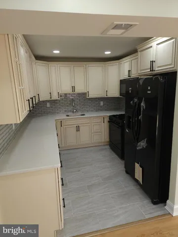 a kitchen with white cabinets and black appliances