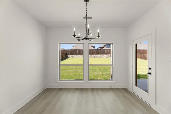 a view of a room with wooden floor chandelier and windows