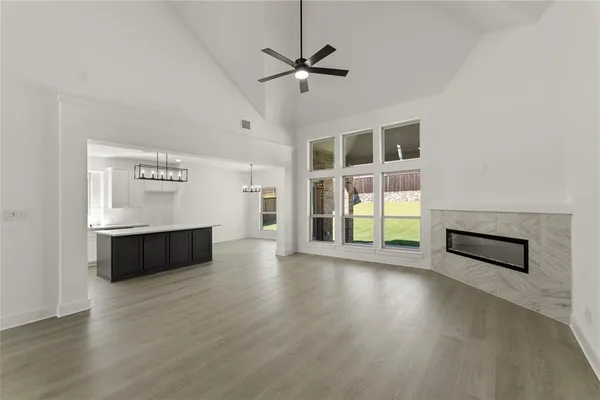 an empty room with wooden floor a ceiling fan and windows