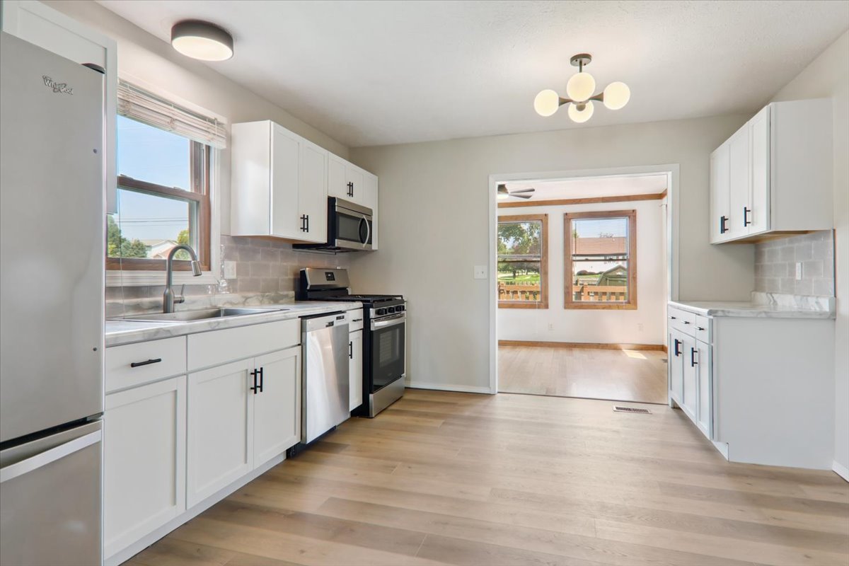 600 Carriage Hills Road, Unit A Normal, IL 61761 - Photo 4 of 19 a kitchen with granite countertop a stove top oven a sink dishwasher and white cabinets with wooden floor