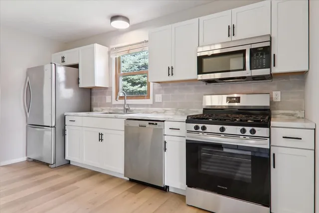 a kitchen with cabinets stainless steel appliances a sink and a window