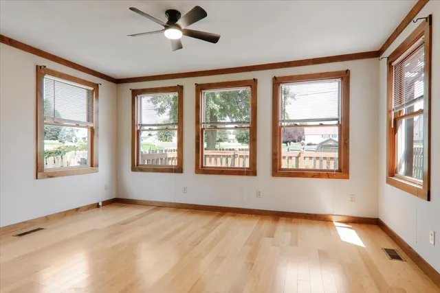 a view of an empty room with a window and wooden floor