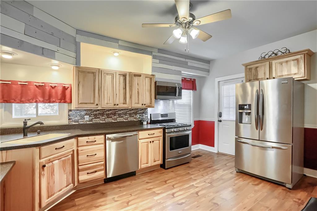 392 Reno Street Rochester, PA 15074 - Photo 16 of 41 a kitchen with stainless steel appliances granite countertop a refrigerator a stove a sink and white cabinets with wooden floor