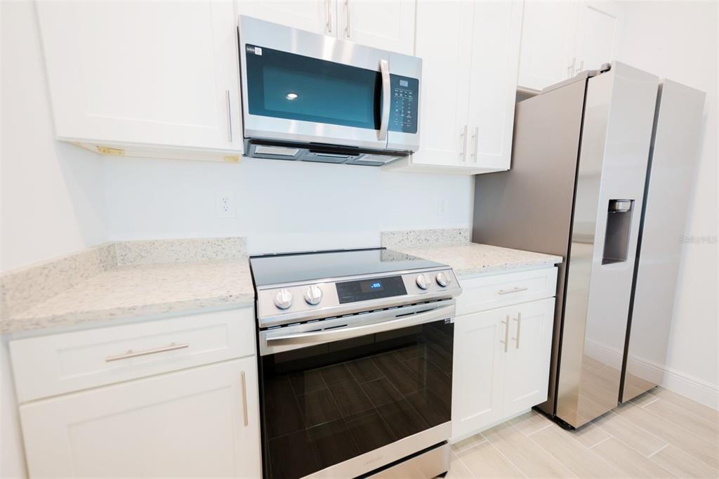 1736 Pacific Road Kissimmee, FL 34759 - Photo 19 of 42 a kitchen with stainless steel appliances white cabinets and a refrigerator