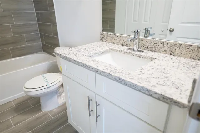 a bathroom with a granite countertop sink a toilet and bathtub