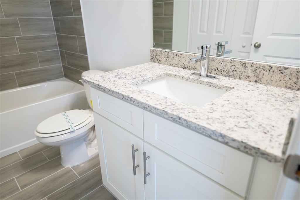 1736 Pacific Road Kissimmee, FL 34759 - Photo 36 of 42 a bathroom with a granite countertop sink a toilet and bathtub