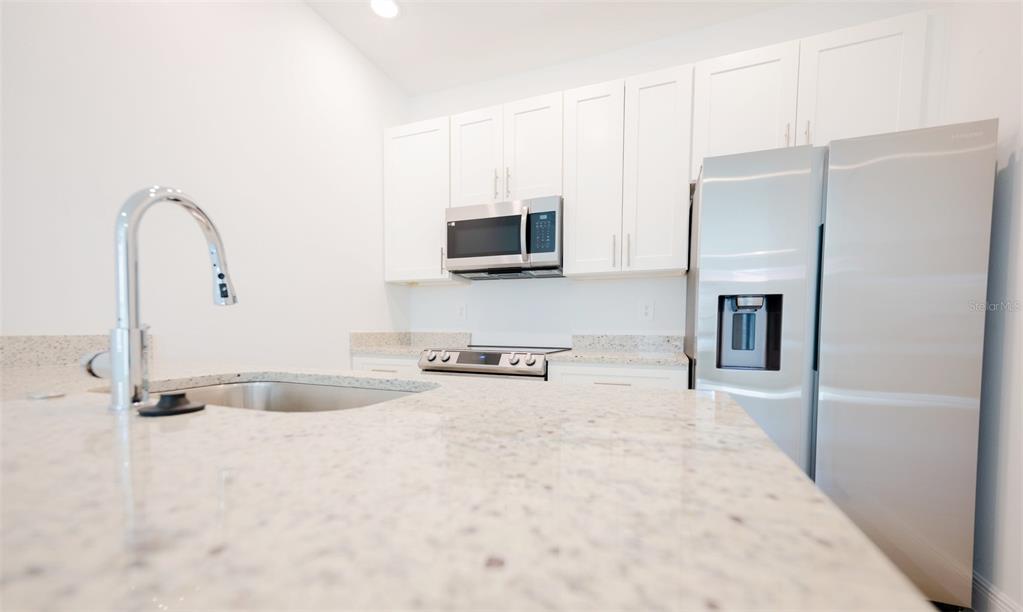 1736 Pacific Road Kissimmee, FL 34759 - Photo 37 of 42 a kitchen with kitchen island a counter top space cabinets and stainless steel appliances
