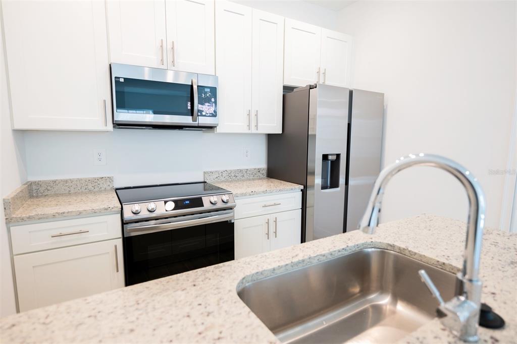 1736 Pacific Road Kissimmee, FL 34759 - Photo 40 of 42 a kitchen with stainless steel appliances granite countertop a refrigerator stove and microwave