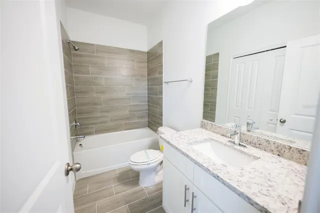 a bathroom with a granite countertop sink a toilet and shower