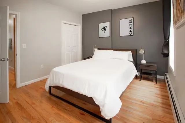 a bed sitting in a bedroom next to a window and a wooden floor