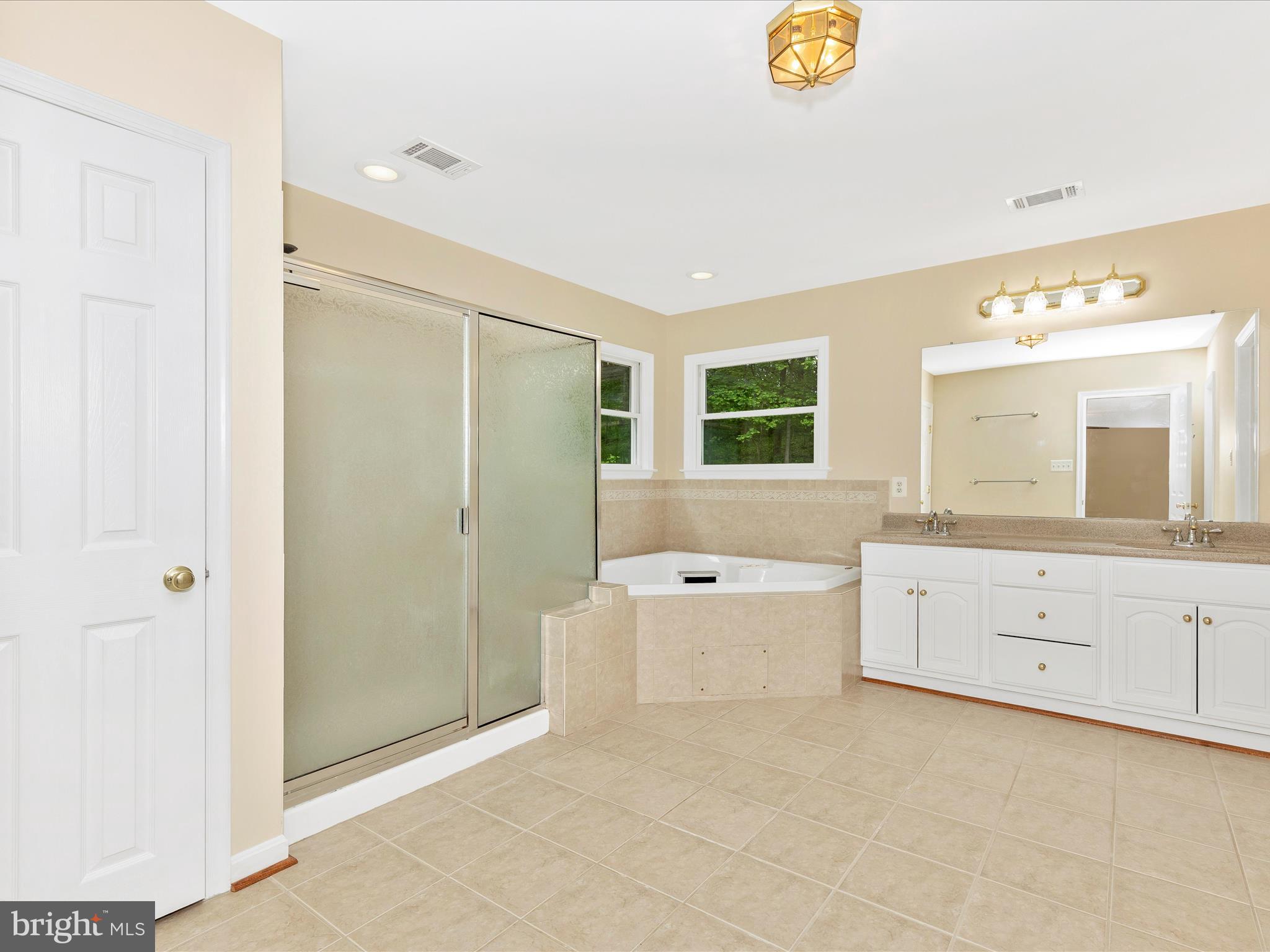 10433 Grindstone Run Road Myersville, MD 21773 - Photo 29 of 42 a spacious bathroom with a double vanity sink a mirror a bathtub and a shower
