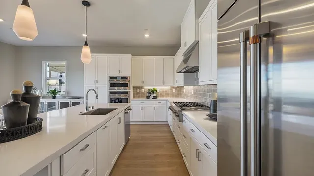 a kitchen with stainless steel appliances granite countertop a sink a stove and a refrigerator