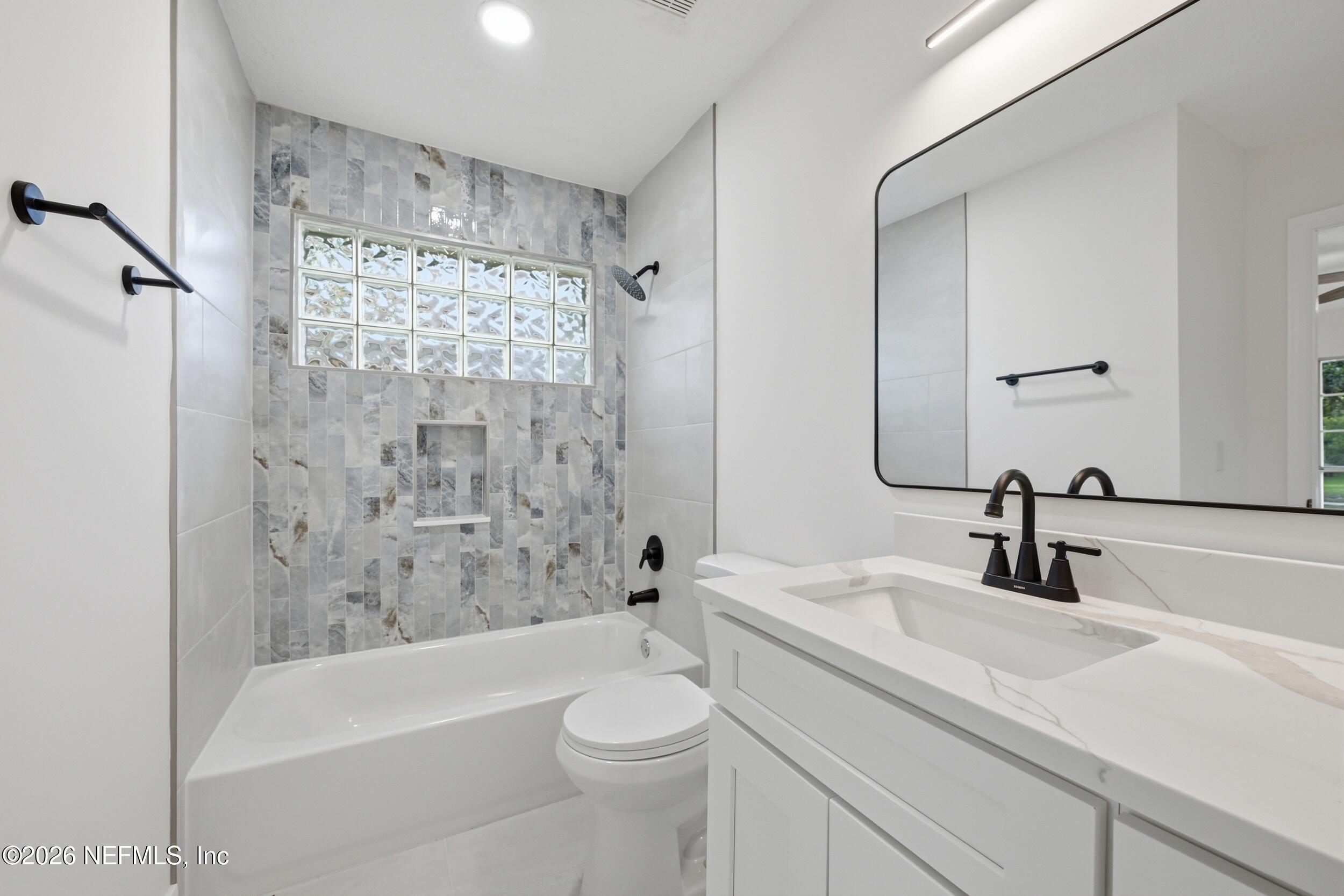 3286 Marbon Road Jacksonville, FL 32223 - Photo 19 of 36 a bathroom with a sink a toilet a mirror a bathtub and shower