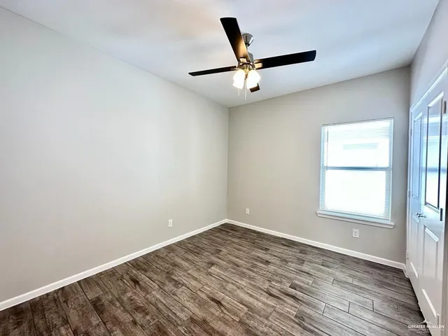 an empty room with a window and ceiling fan