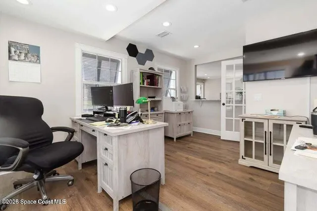 a living room with stainless steel appliances furniture a flat screen tv and kitchen view