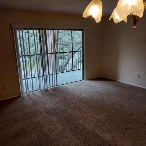 a view of an empty room with a chandelier fan